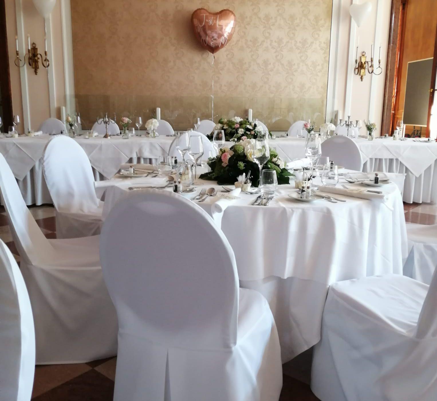 Eleganter Festsaal mit runden Tischen, weißen Tischdecken und Stuhlhussen zum Mieten für Hochzeiten und Galas in Salzburg und Oberösterreich.