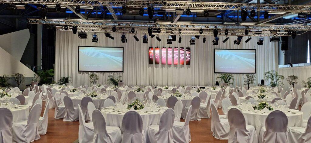 Elegante Festhalle mit Stuhlhussen und geschmückten Tafeln für Event