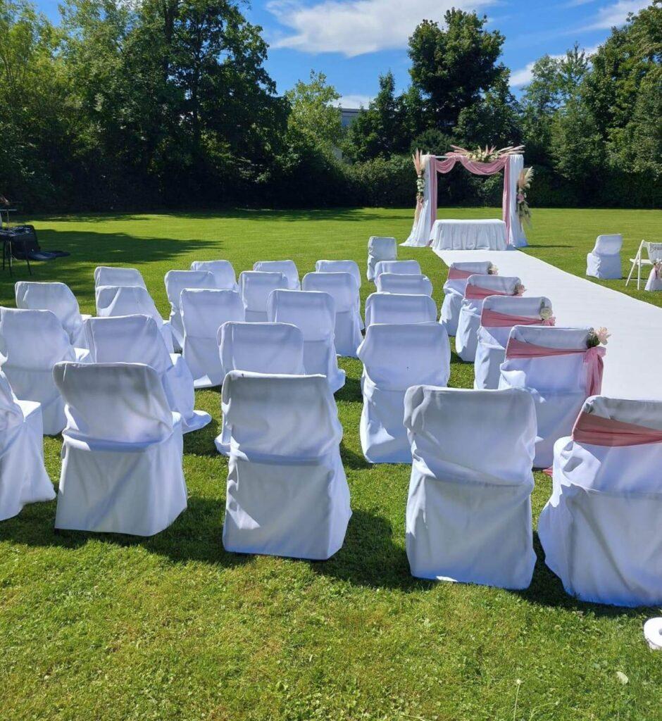 Elegante freie Trauung im Park Kavalierhaus in Salzburg mit weißen Stuhlhussen und Hochzeitsbogen – Ihr Experte für Hochzeitsdekoration in Österreich