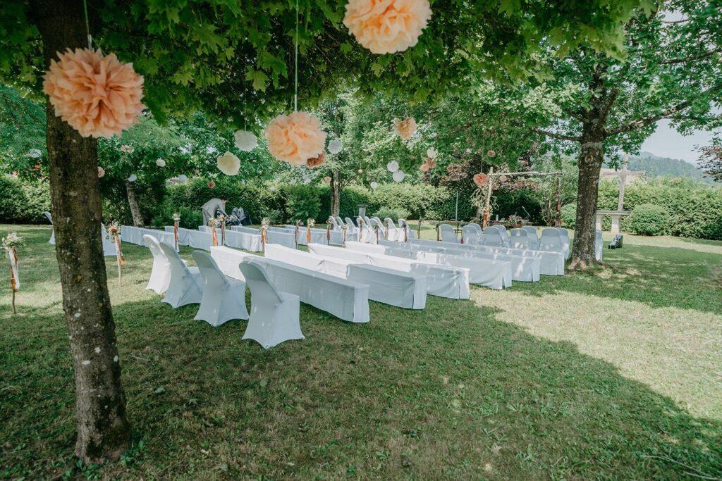 Romantische Gartenhochzeit in Salzburg mit weißen Bierbankhussen und hängenden Pompoms – Verleih für Hochzeitsdekoration in Österreich.