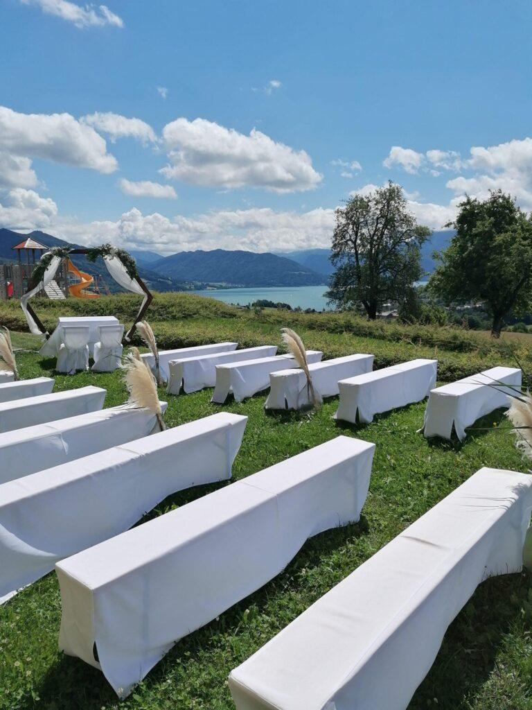 Freie Trauung am Mondsee mit weißen Bierbankhussen und Traubogen – Verleih für Hochzeitsdeko in Salzburg und Oberösterreich